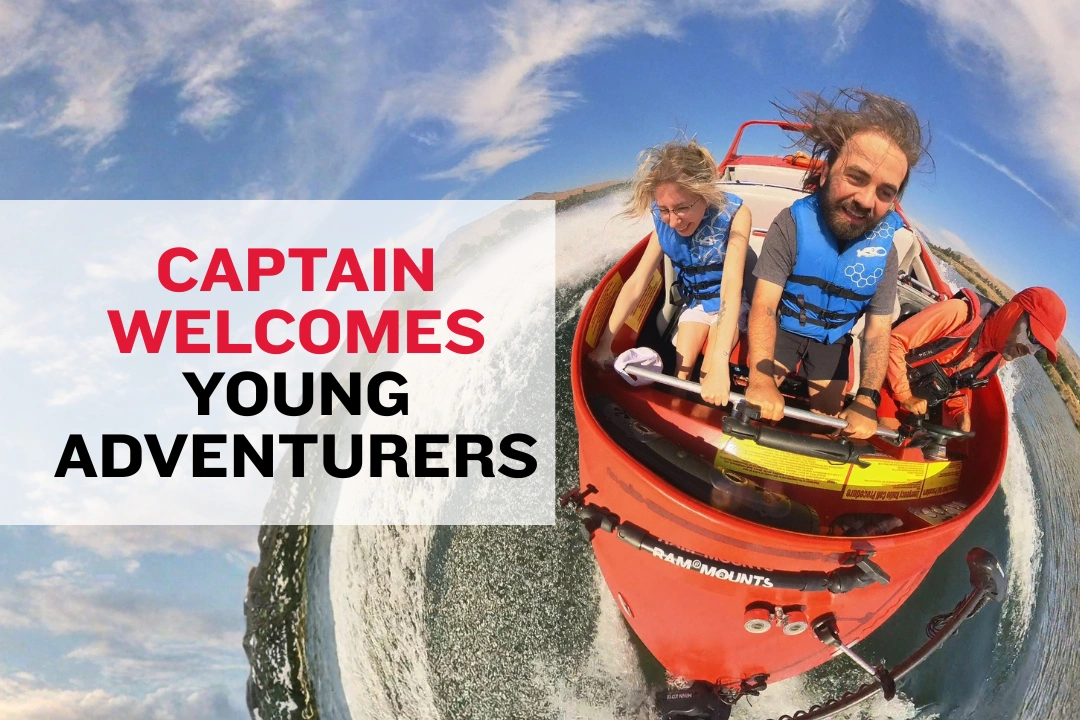 Boat captain kneeling to talk with children in life jackets before departure